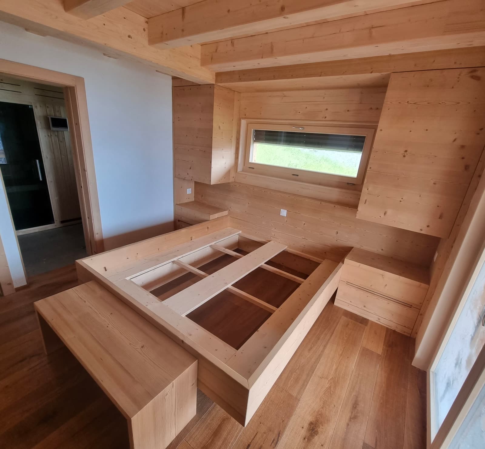 Chambre de chalet contemporaine : lit, placards intégrés et boiseries en bois clair réalisés sur-mesure.