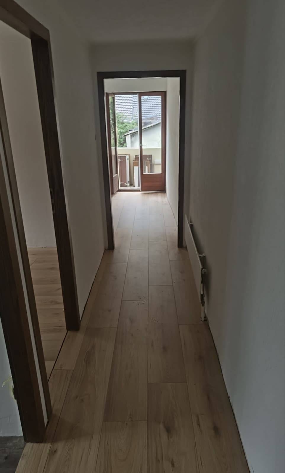 Couloir en cours de rénovation, parquet en bois clair fraîchement posé et murs en préparation.